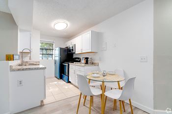 A kitchen and dining area with a small table and chairs